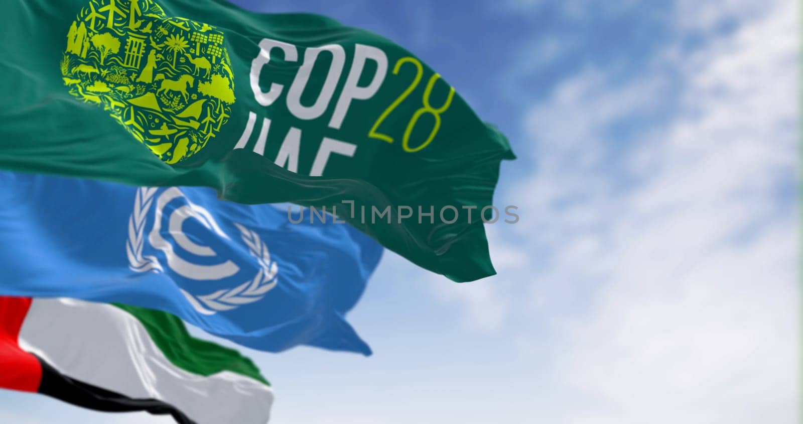 Dubai, UAE, Nov. 30 2023: Flags of COP28, UNFCCC and UAE waving on a clear day. 3d illustration render. Selective focus. Rippling fabric