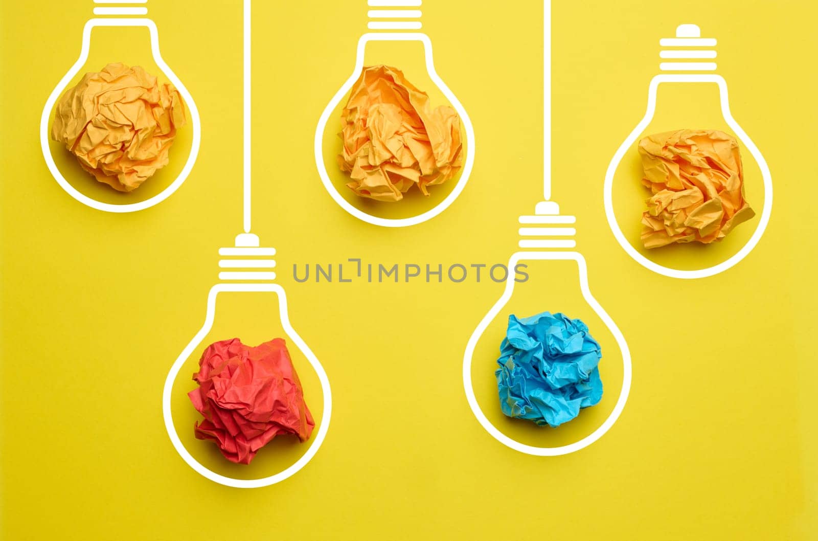 Crumpled balls of paper inside an electric lamp on a yellow background. Concept of new ideas, brainstorming