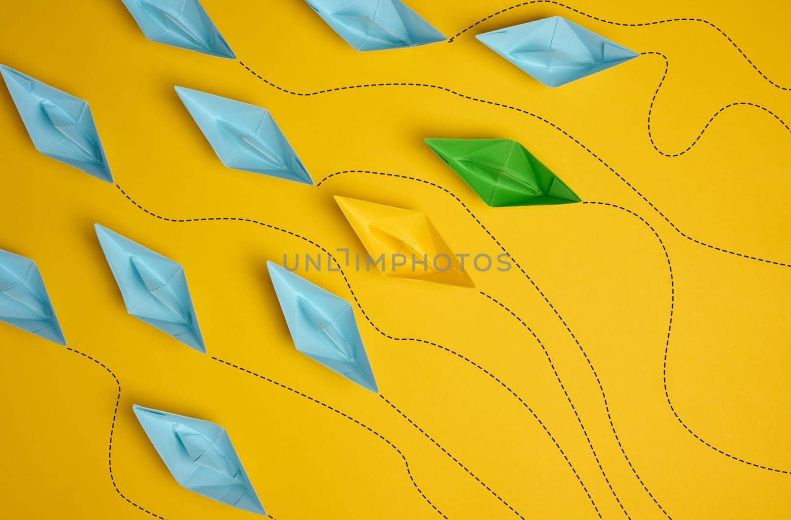 Paper boats on a yellow background with paths of movement, representing the concept of individuality. Top view