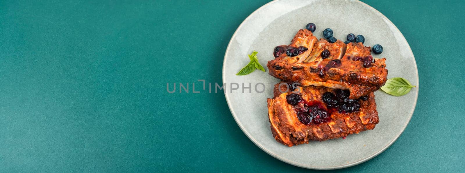 Delicious fried pork ribs with blueberry sauce. Restaurant menu. Space for text.