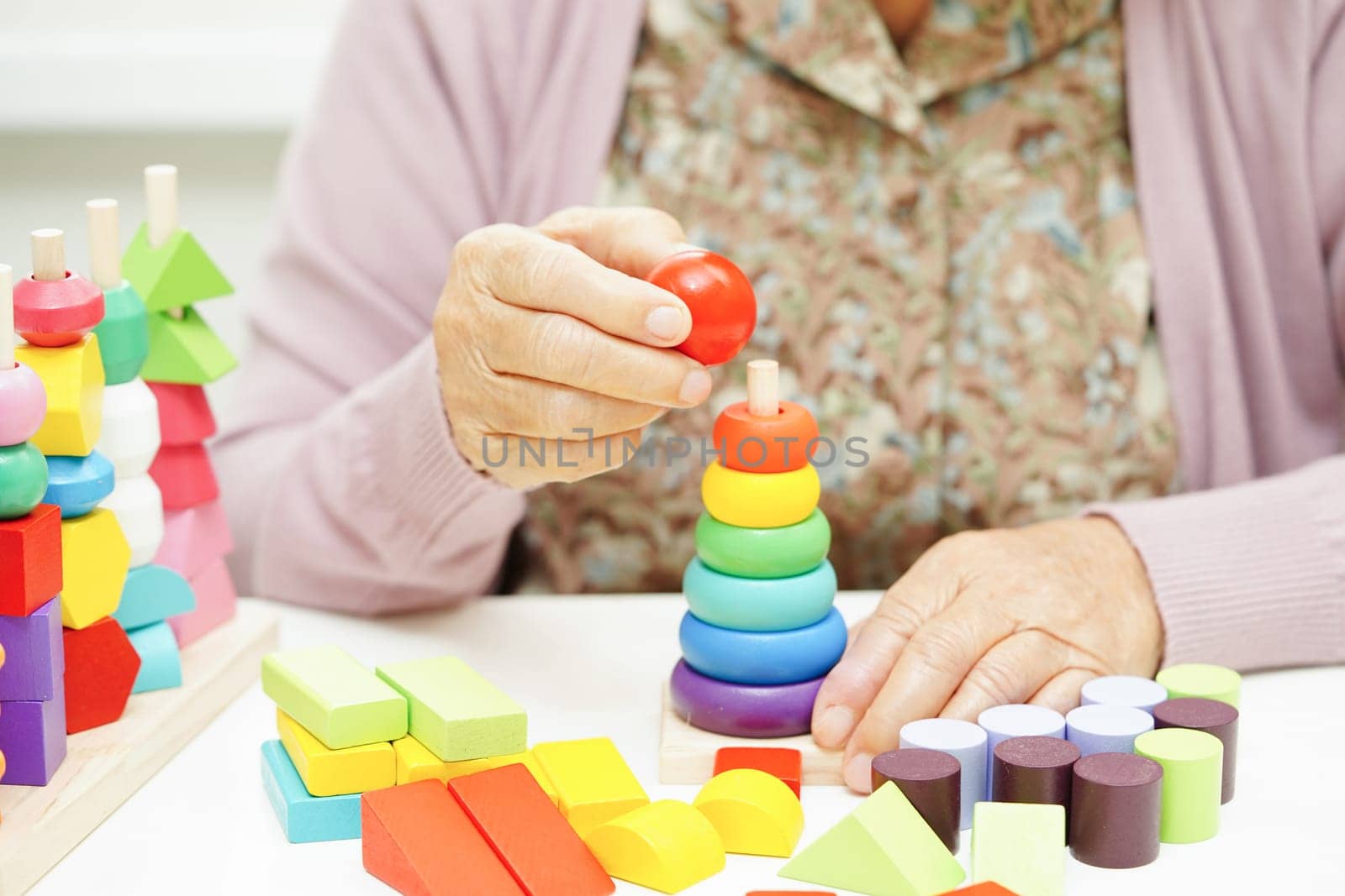 Asian elderly woman playing puzzles game for treatment dementia prevention and Alzheimer disease.
