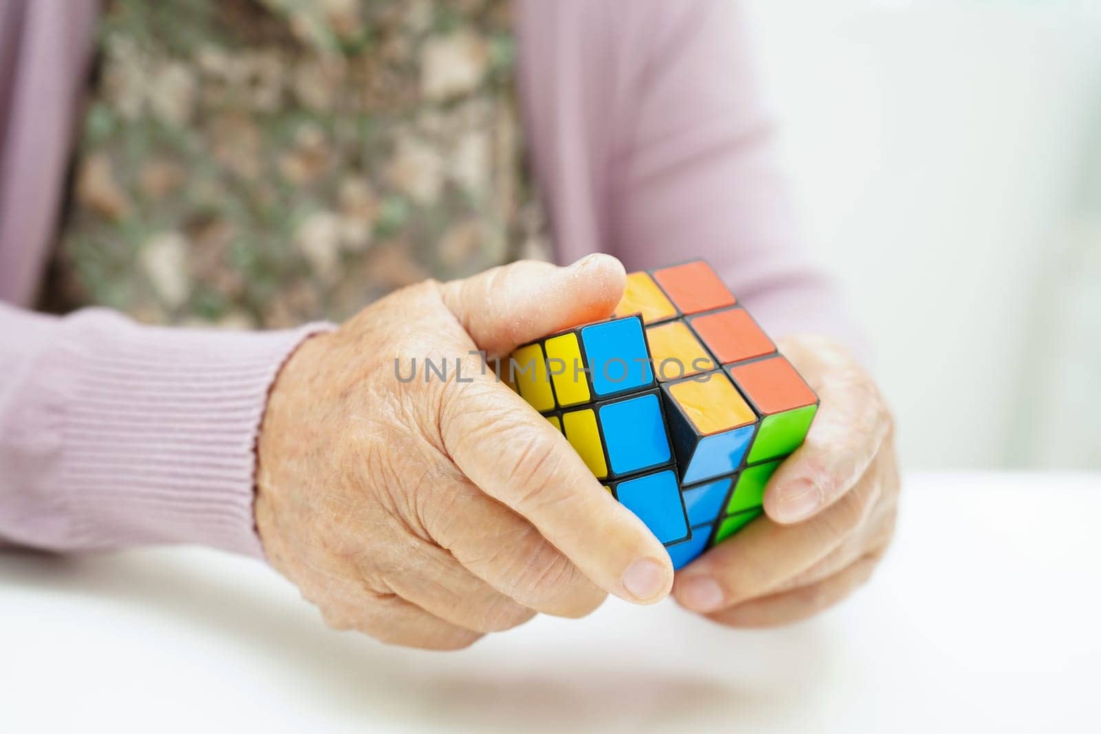 Bangkok, Thailand - May 15, 2022 Asian elderly woman playing Rubik cube game for treatment dementia prevention and Alzheimer disease.