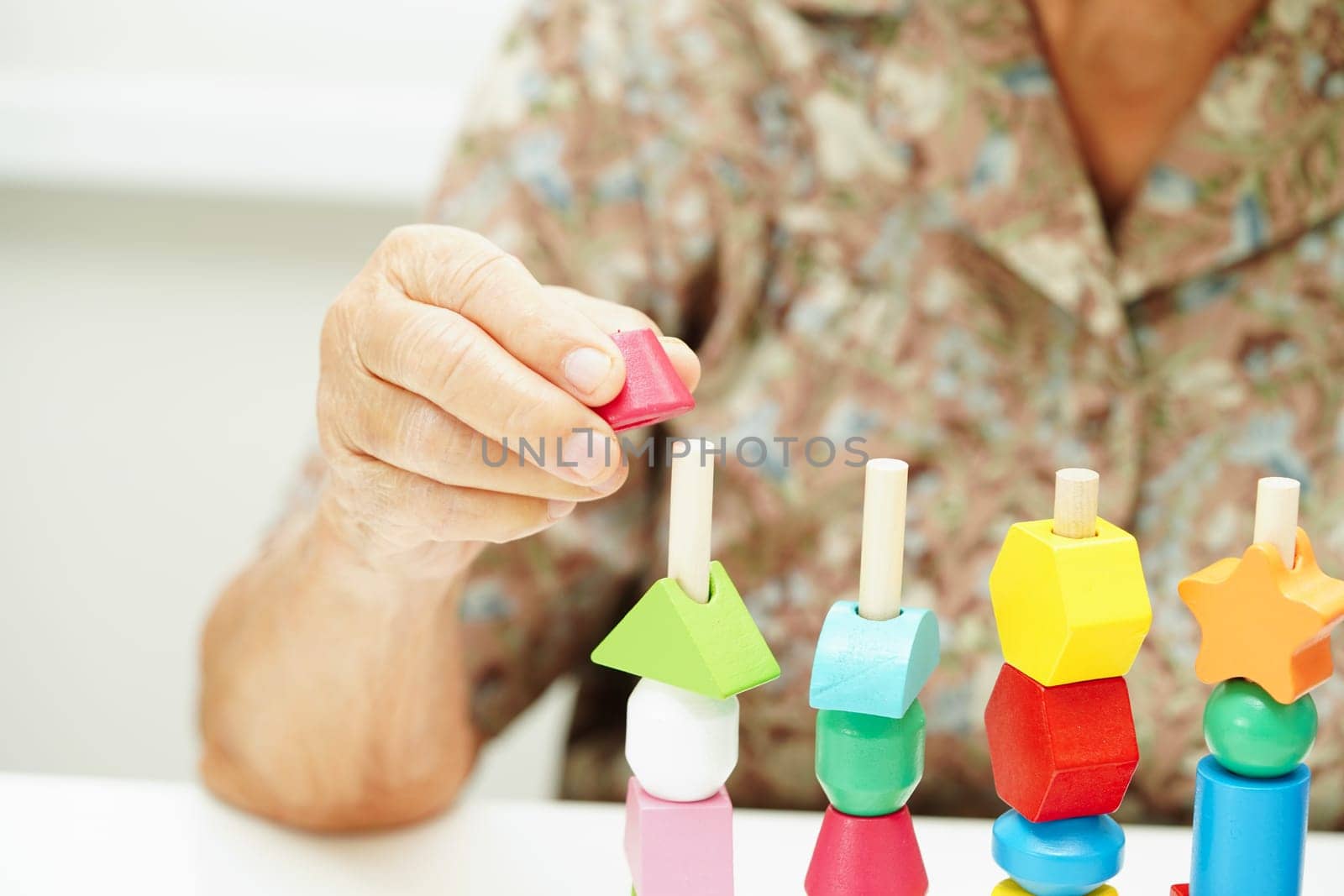 Asian elderly woman playing puzzles game for treatment dementia prevention and Alzheimer disease.