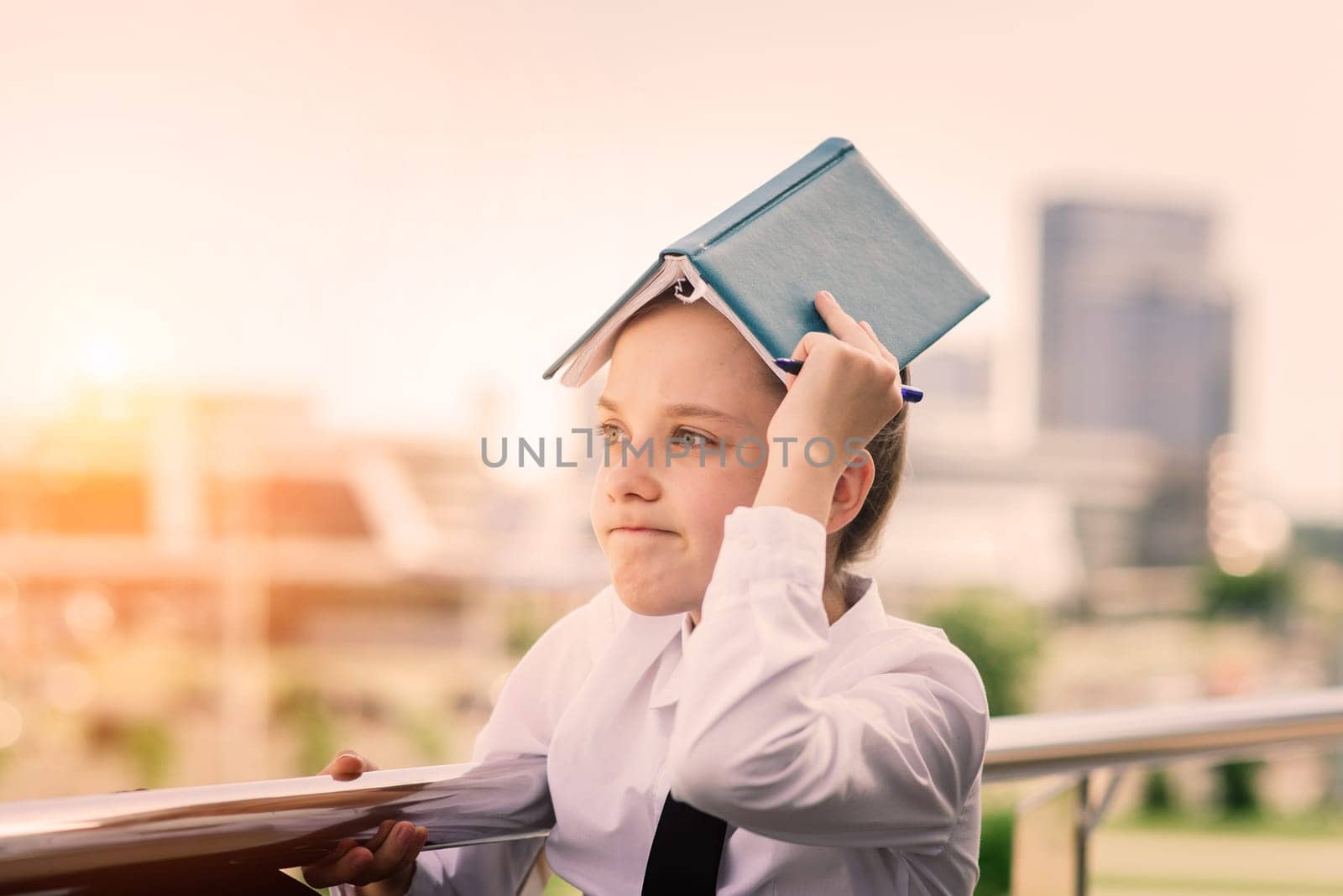 Teenager girl in summer in city park resting after school and college lessons, notebook in her hands.