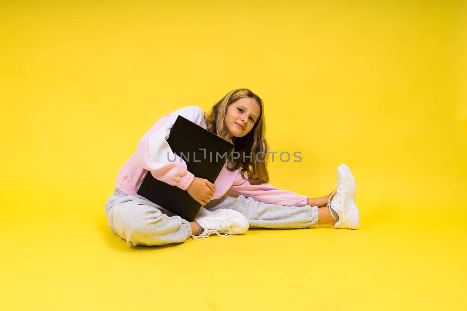Fitness online. Girl doing stretching exercise on a floor alone with laptop at studio
