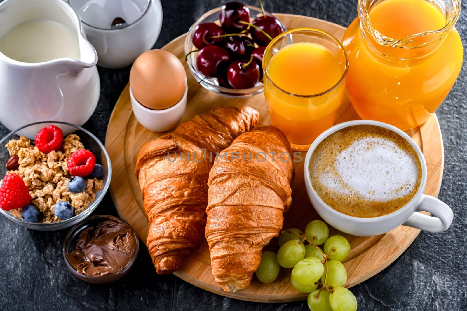 Breakfast served with coffee, orange juice, egg, cereals and croissants.