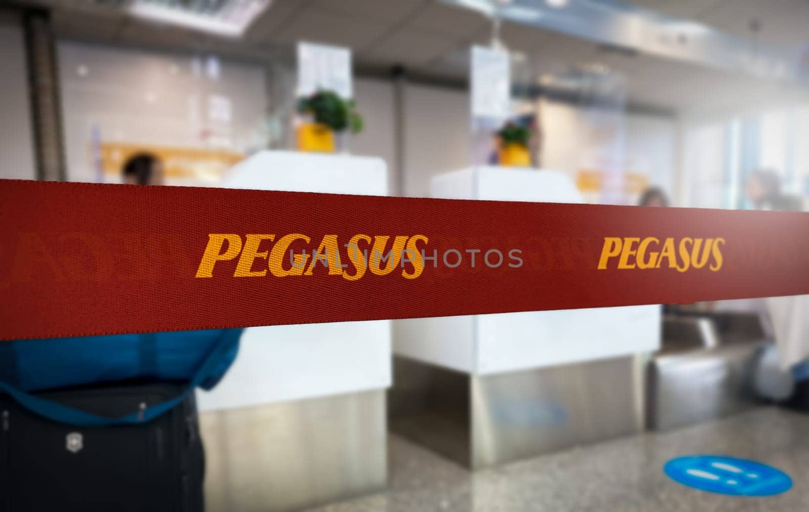 Istanbul, TR, 30 Nov. 30 2023: Vibrant red queue divider with Pegasus Airlines branding in bold yellow letters, prominently displayed in a blurred airport check-in area