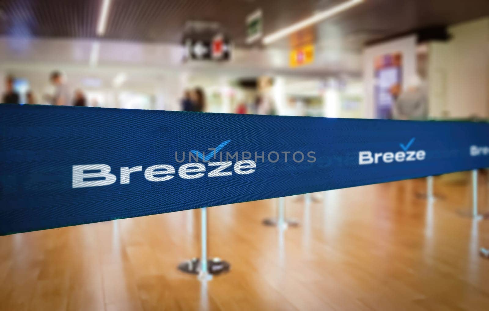 Charleston, US, Nov. 28 2023: Selective focus on a blue textured Breeze Airways branded ribbon used as a queue divider at an airport terminal, with blurred background