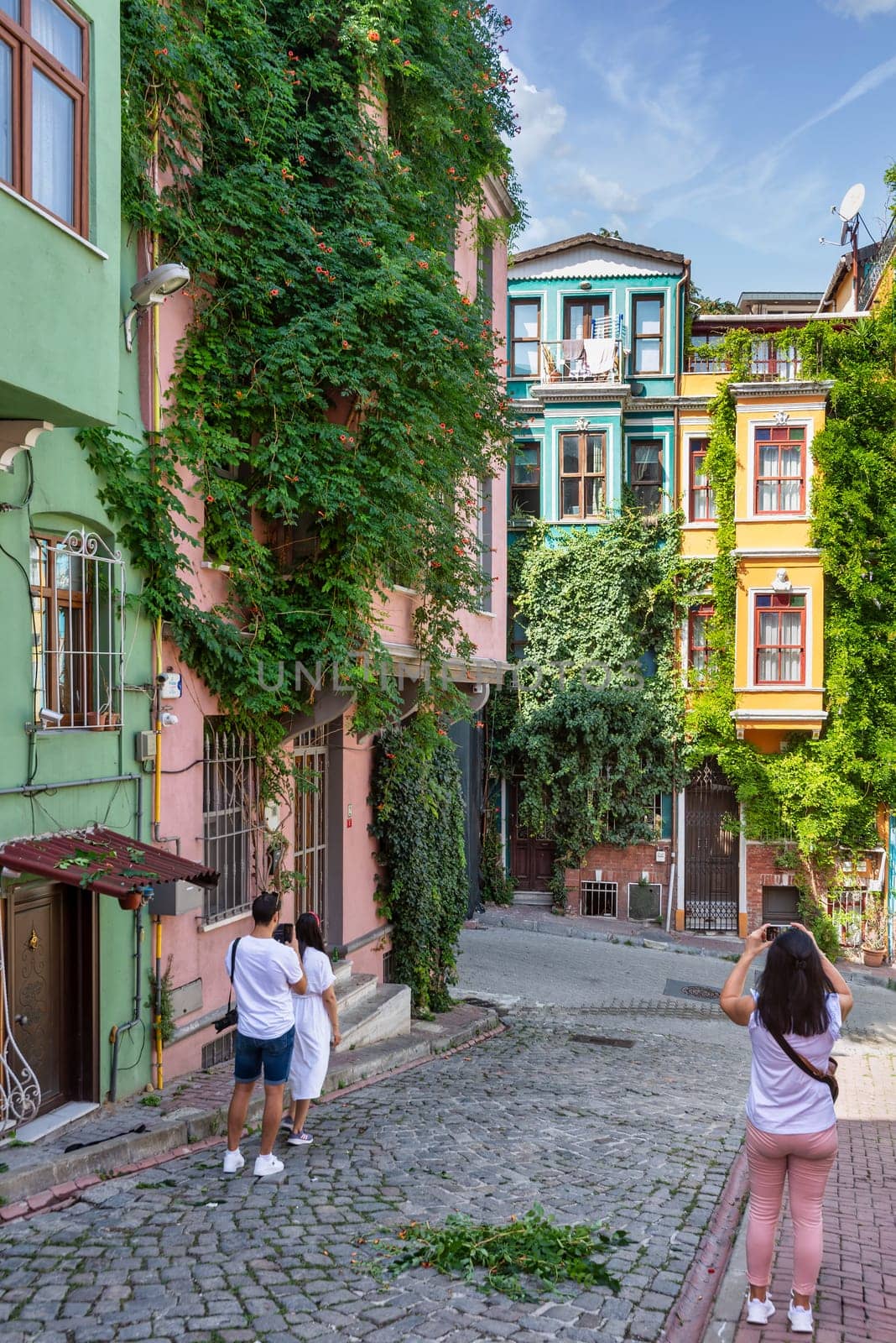Istanbul, Turkey - August 28, 2022: Tourists taking memorial photos in front of traditional colorful traditional houses in old Balat district, in a summer day