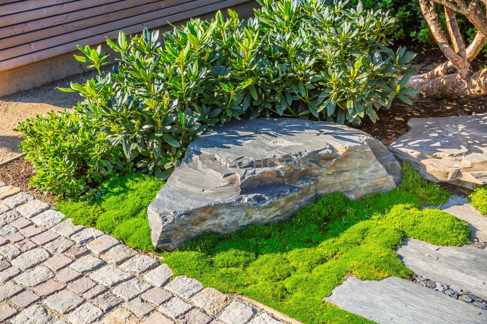 Detail of garden path with stone slabs with bark mulch and native plants. Landscaping and gardening concept.