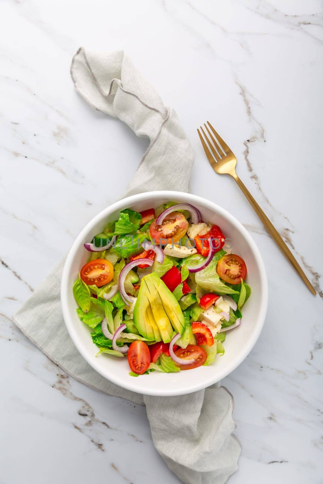 Healthy green salad with avocado, tomatoes, mozzarella and red onions