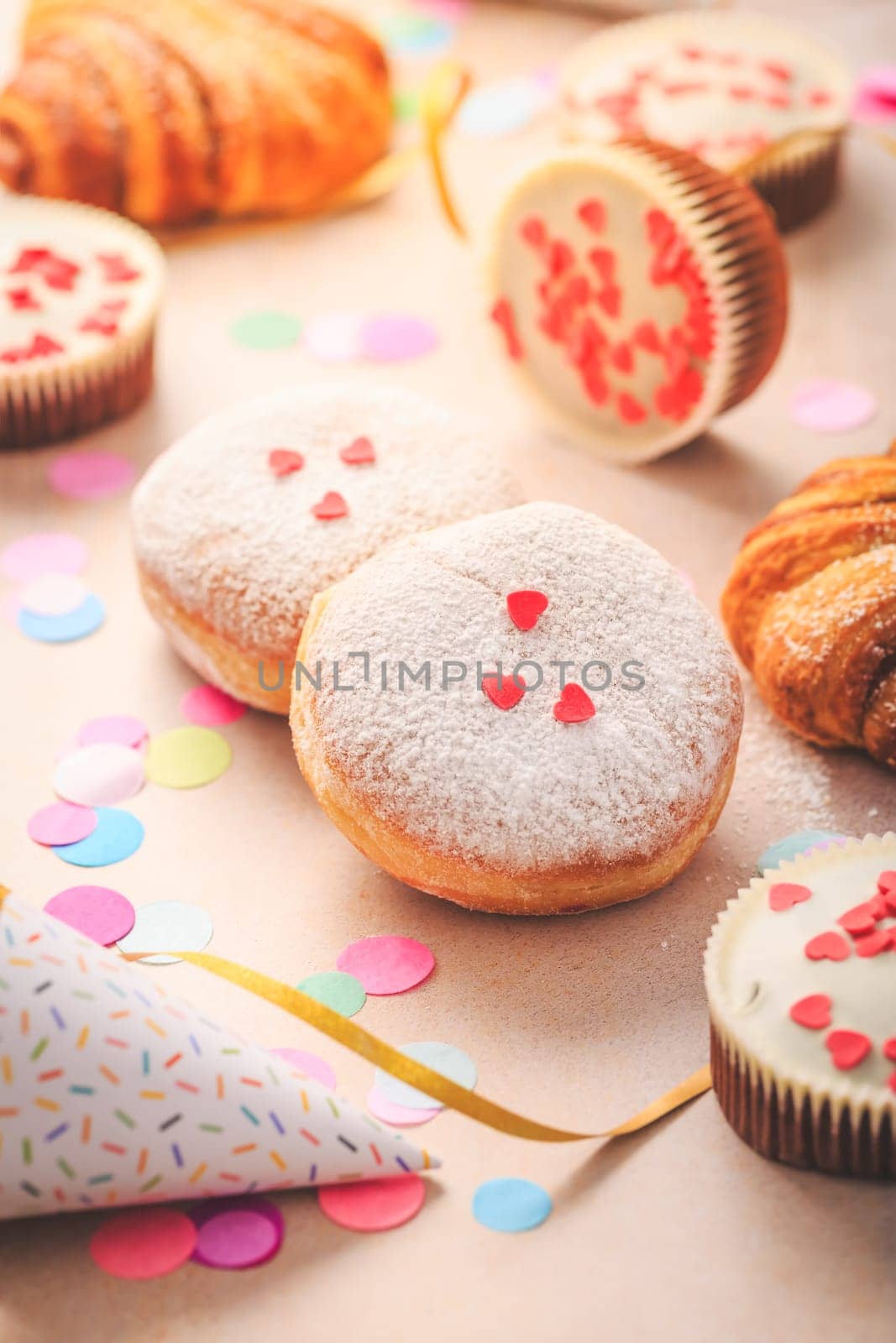 Berliner, cinnamon rolls and cupcakes for carnival and party. German Krapfen or donuts with streamers and confetti. Colorful carnival or birthday image