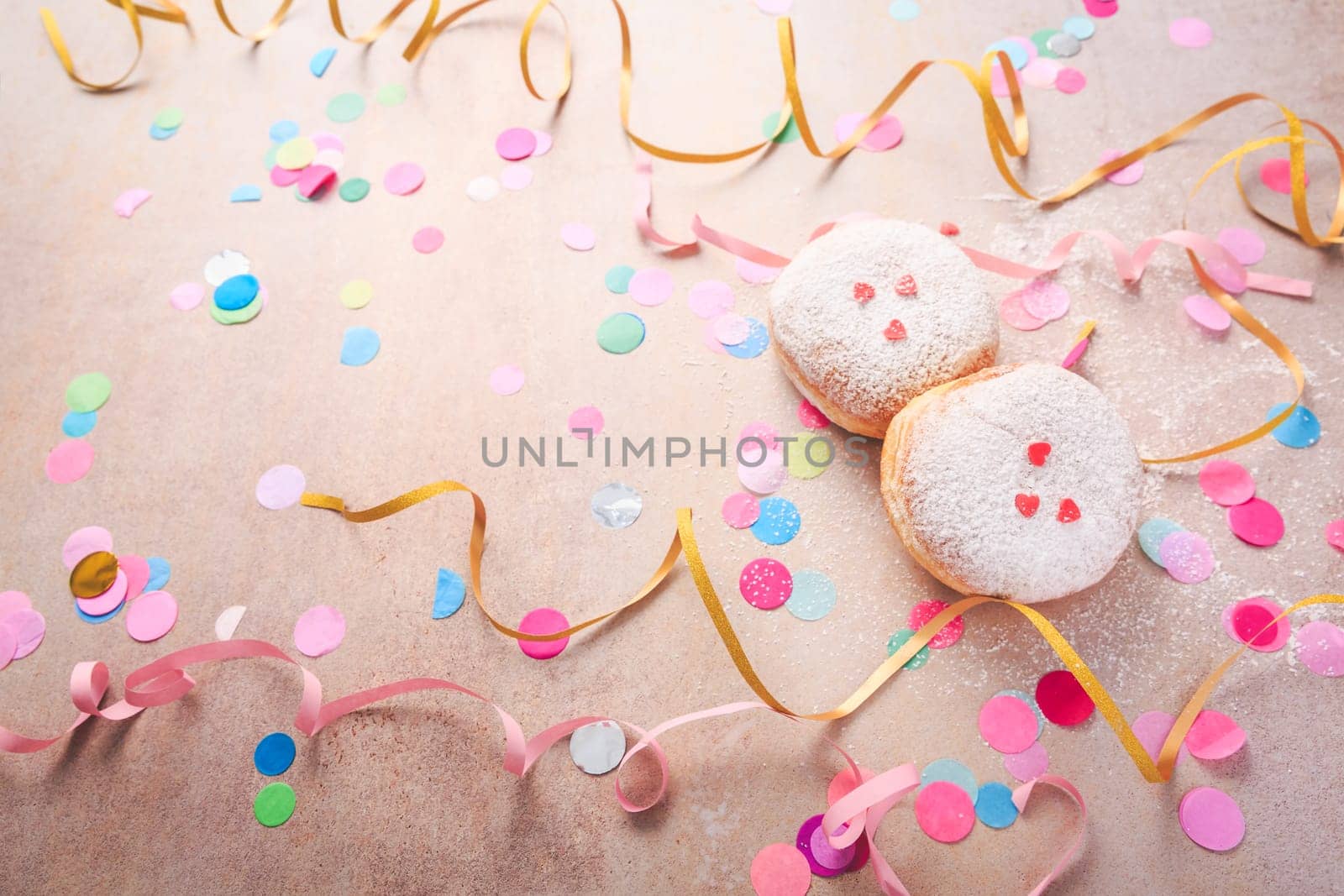 Traditional Berliner for carnival and party. German Krapfen or donuts with streamers and confetti. Colorful carnival or birthday image