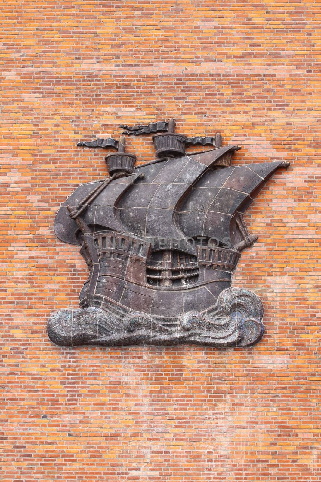 Sailing ship made of metal, on a wall with red bricks
