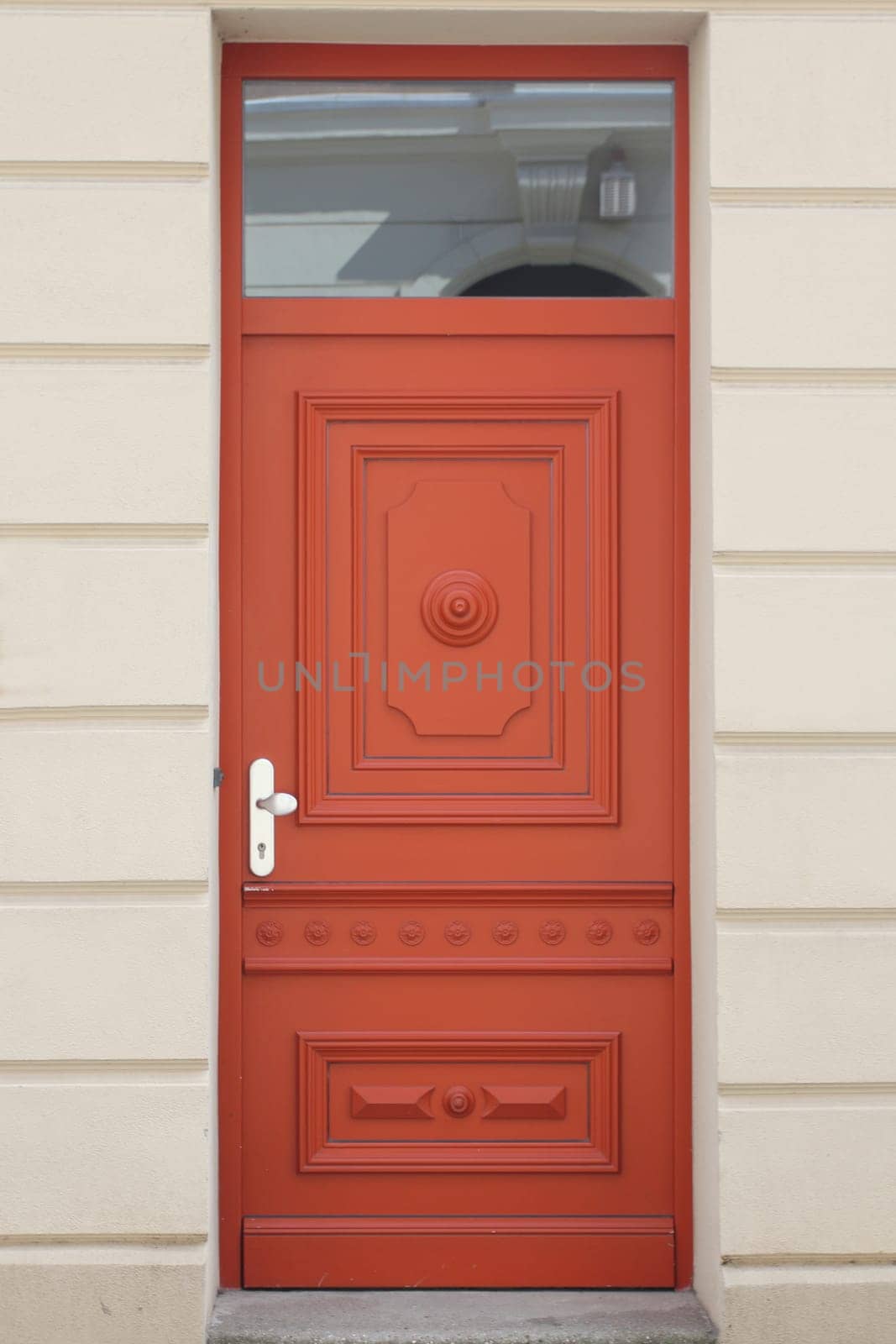 A decorated, red lacquered front door in front of a white background