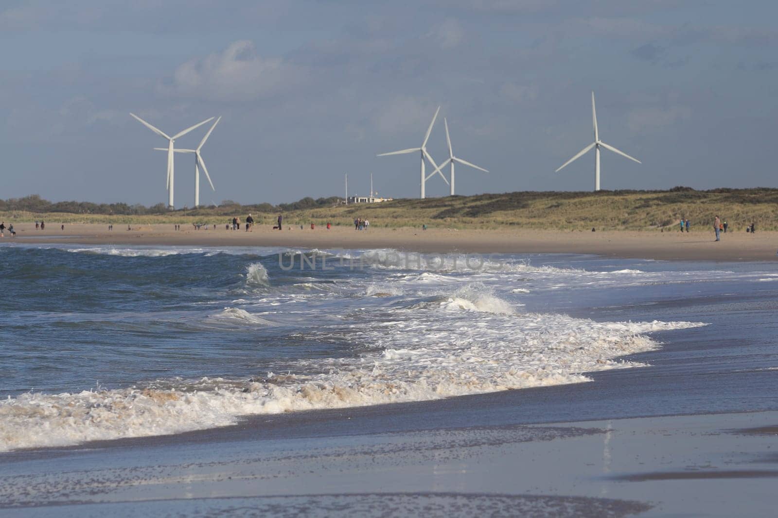 several wind turbines, with beach and the sea in the foreground