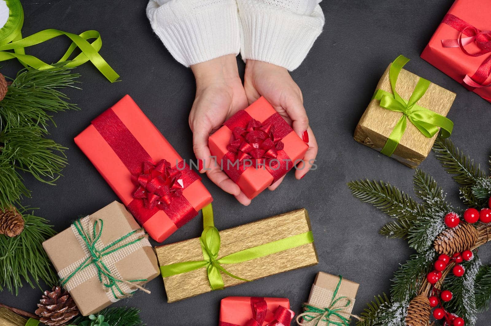 Woman is packing gifts, the pre-holiday bustle and preparations for Christmas. Gifts wrapped in brown paper and tied with green ropes are laid out on the table