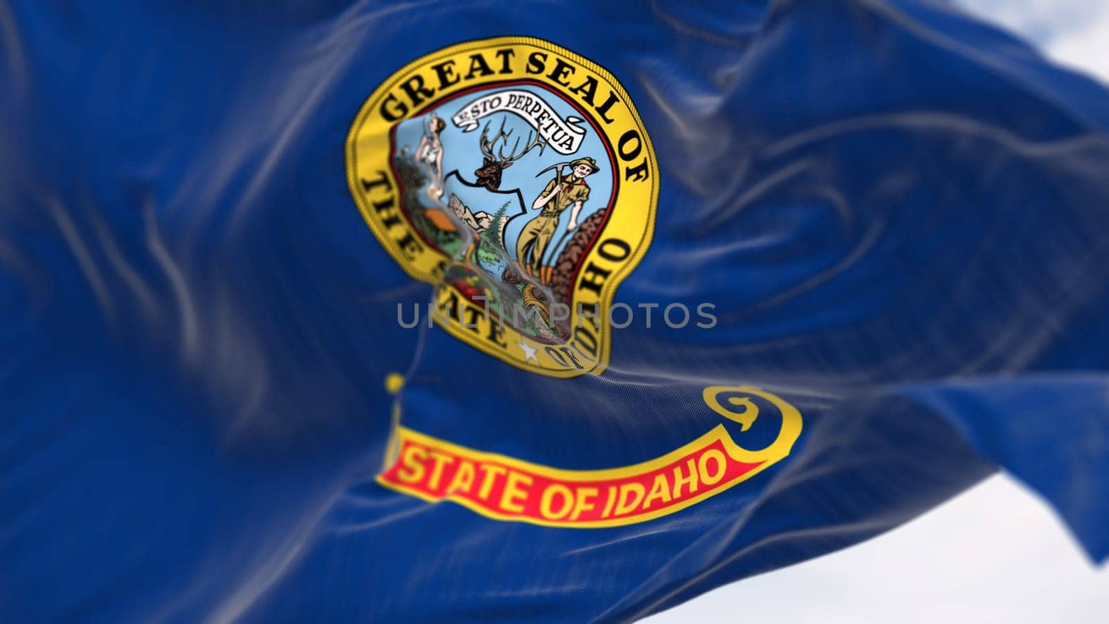 Close-up of Idaho state flag waving on a clear day. State seal in a dark blue area with the words State of Idaho in gold letters on a band under the seal. 3d illustration render. Selective focus