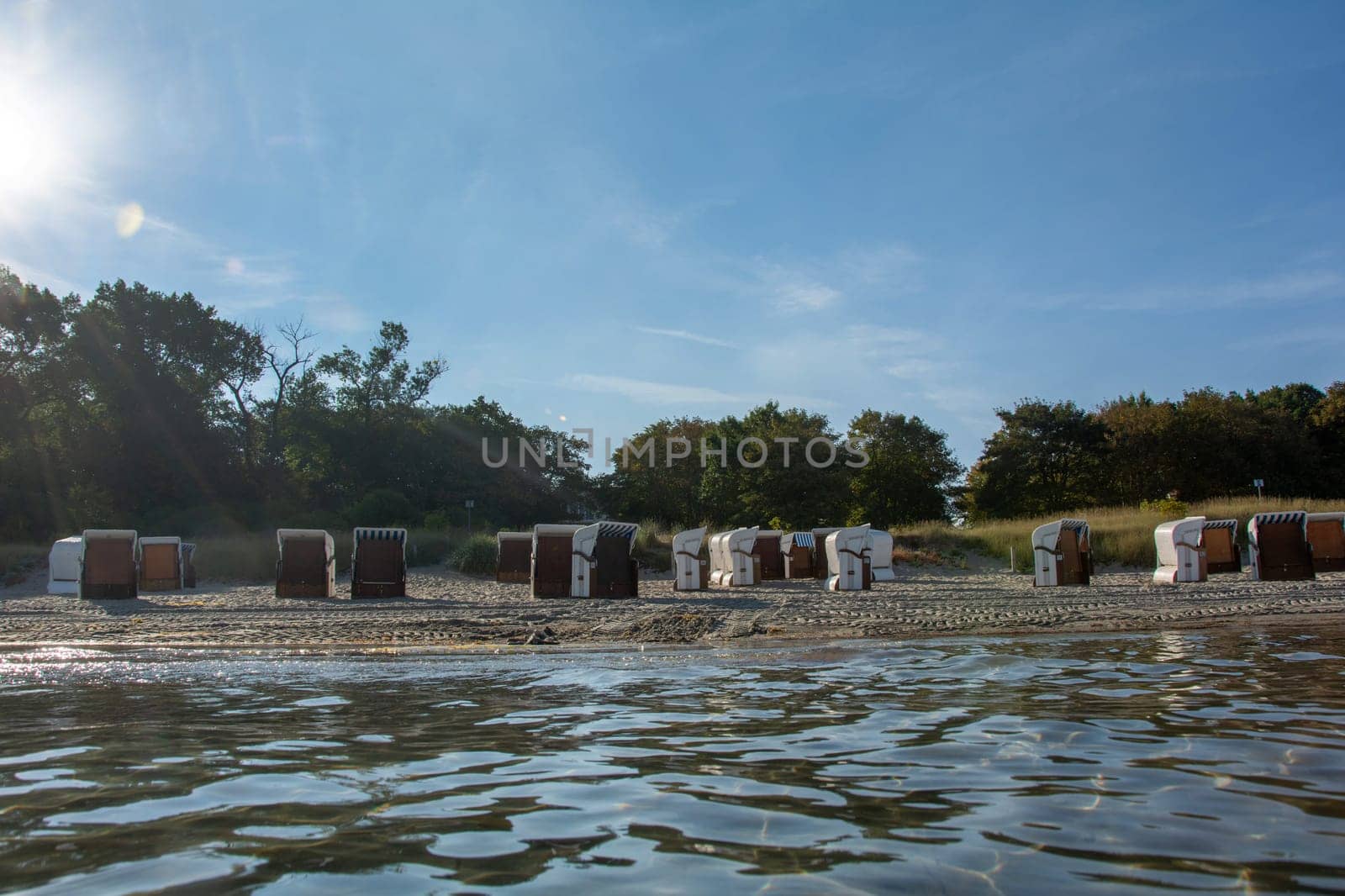 View of beach chairs on the sandy beach from the water of the Baltic Sea, with sun,on Poel, Germany