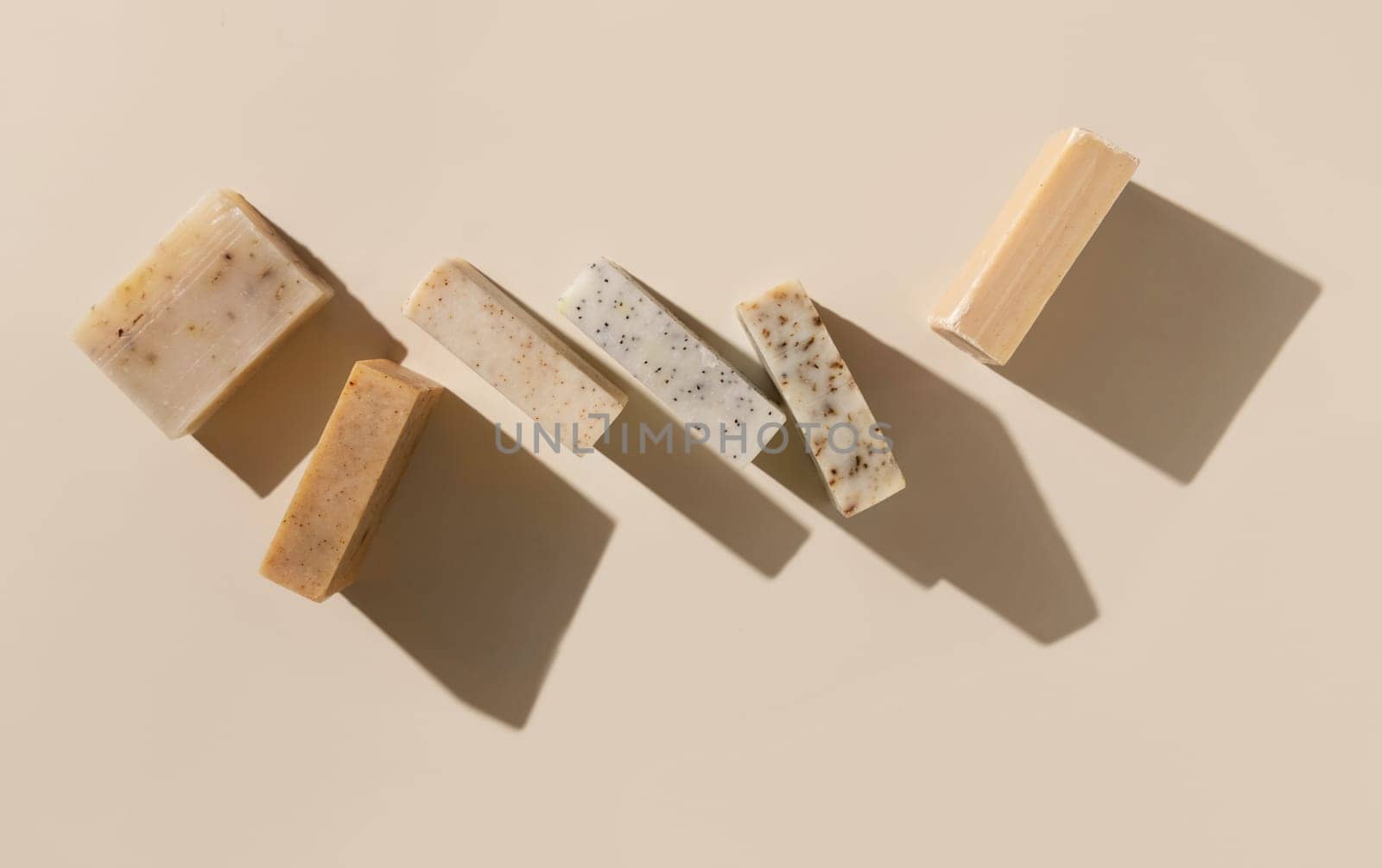 Natural herbal beige and brown handmade soap bars on light beige top view, hard shadows. Hygiene products for Spa and skin care. Using organic handmade soaps