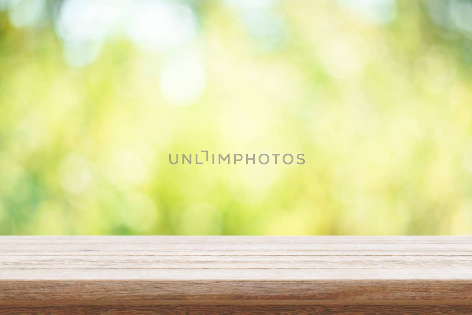 Empty wooden table and green bokeh nature background. Outdoor mockup for food product display montage. Summer garden blur backdrop and rustic desk placement.