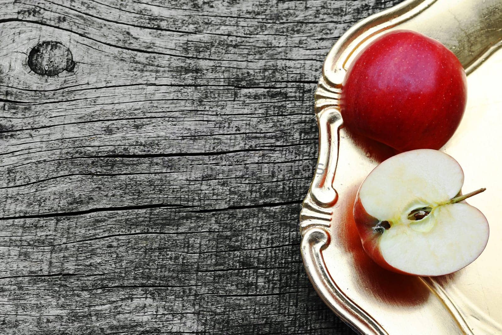 An apple on a golden plate on a wooden table