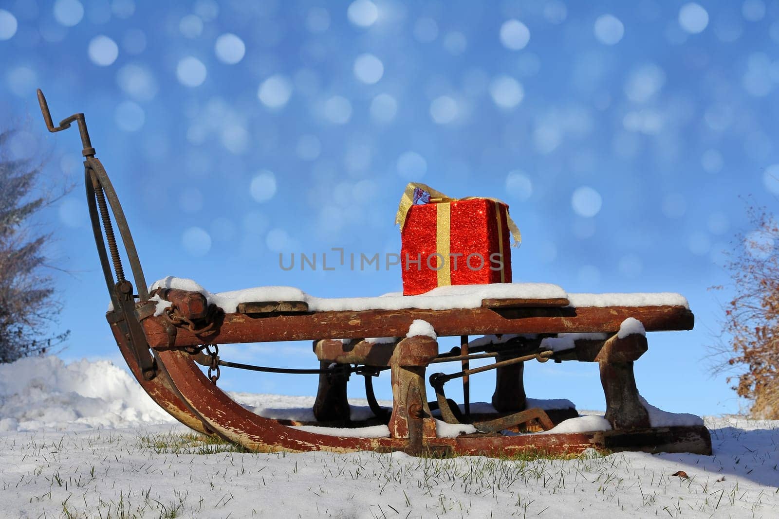 A large red gift package on a wooden sleigh with snow crystals in the sky