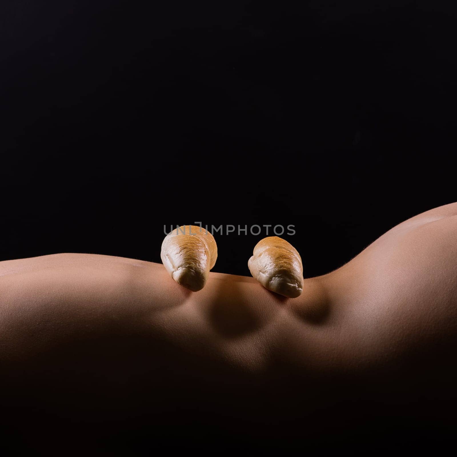 Female sensual body holding one big a white bread bun with sesame seeds, horizontal picture