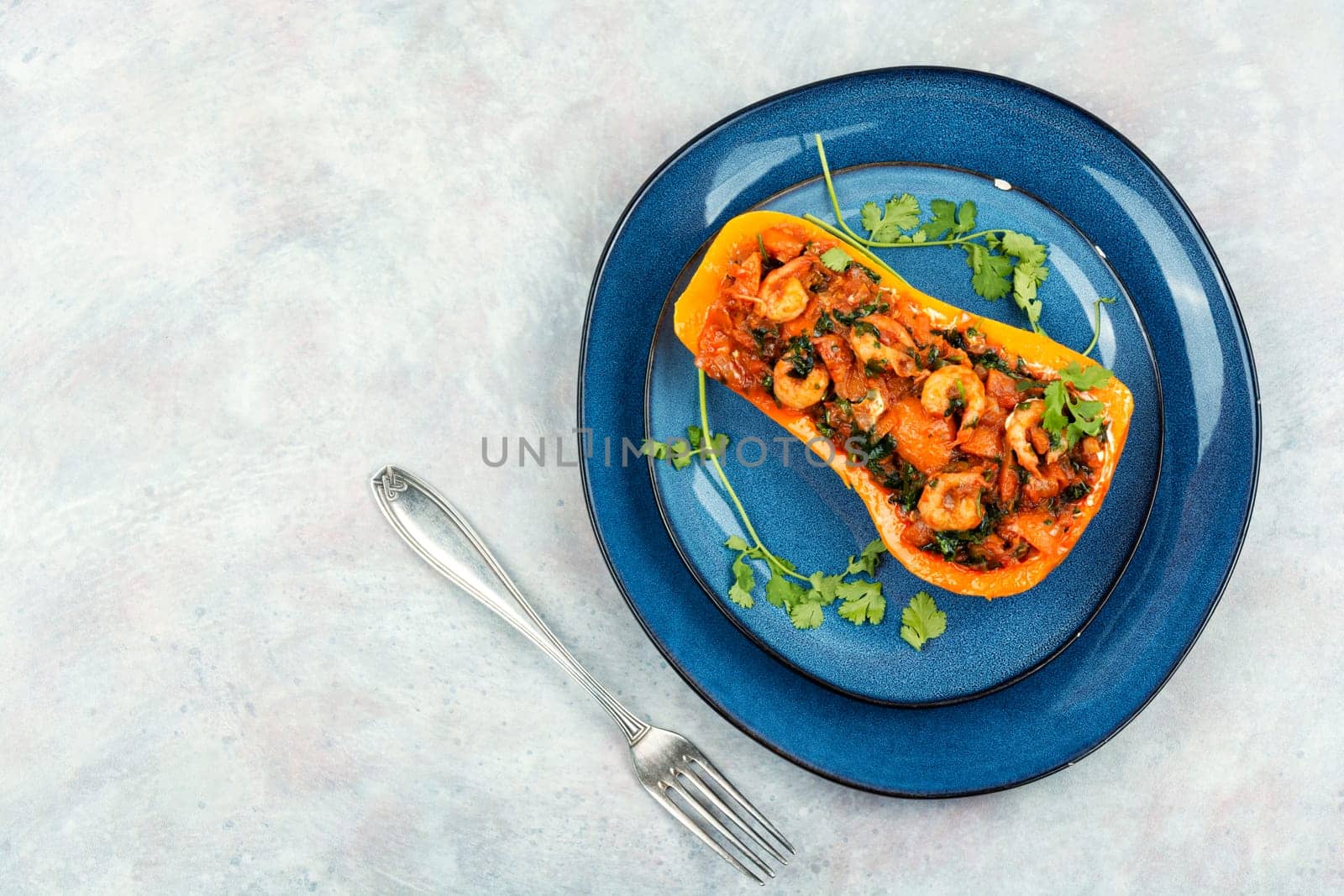 Half a butternut pumpkin stuffed with vegetables and shrimp. Flat lay. Copy space.