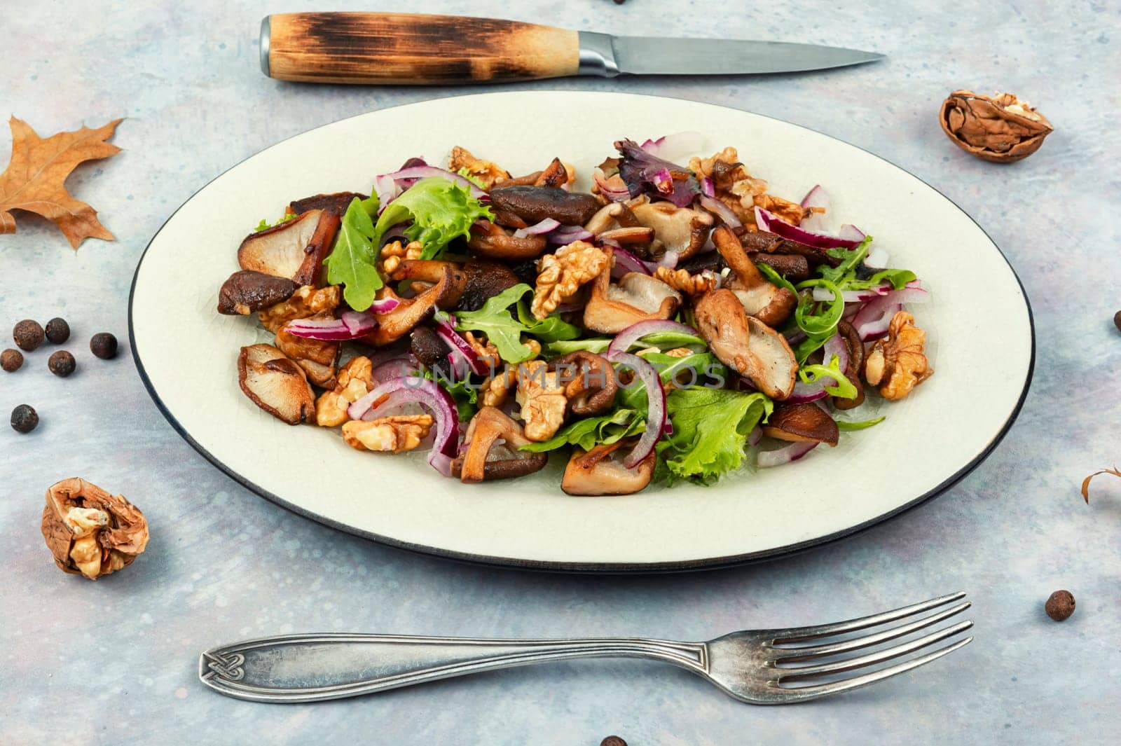 Autumn salad with stewed mushrooms, onions, lettuce and walnuts. Concept healthy food.