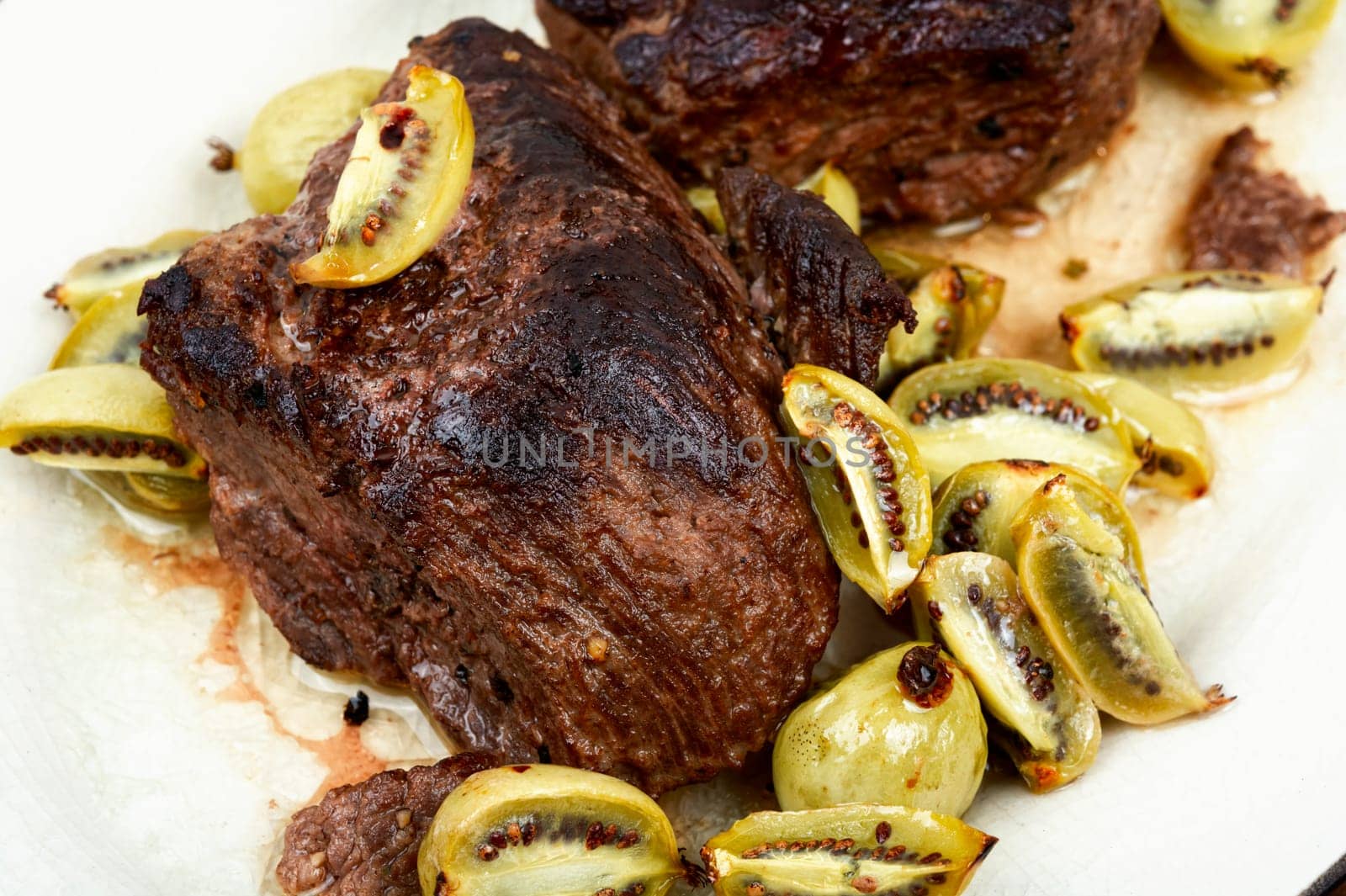 Roasted ostrich steak and mini kiwi on a plate