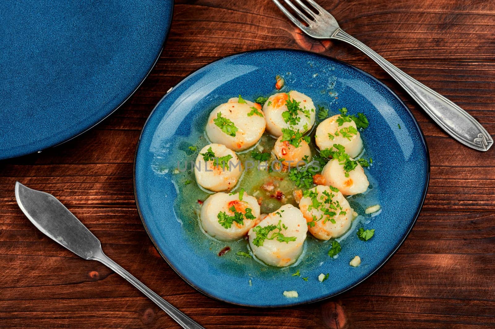 Fried delicious scallops with green on a plate