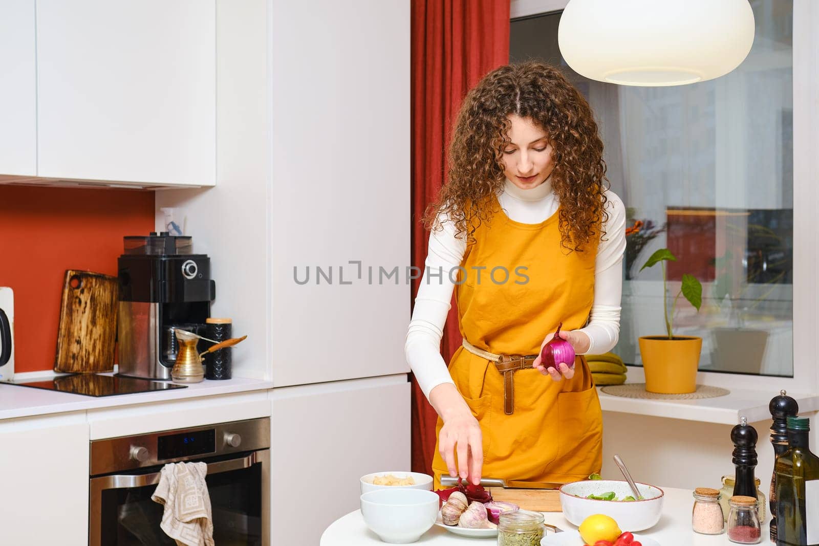 Young woman peeling red onion in the kitchen