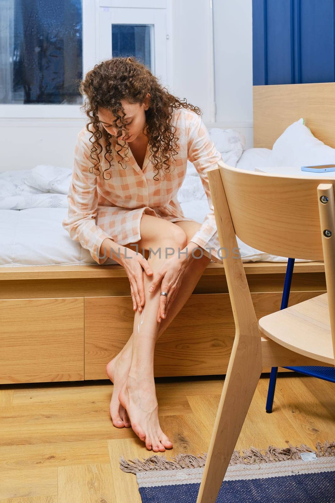 Cute young woman rubbing nourishing body lotion, softening skin after shaving