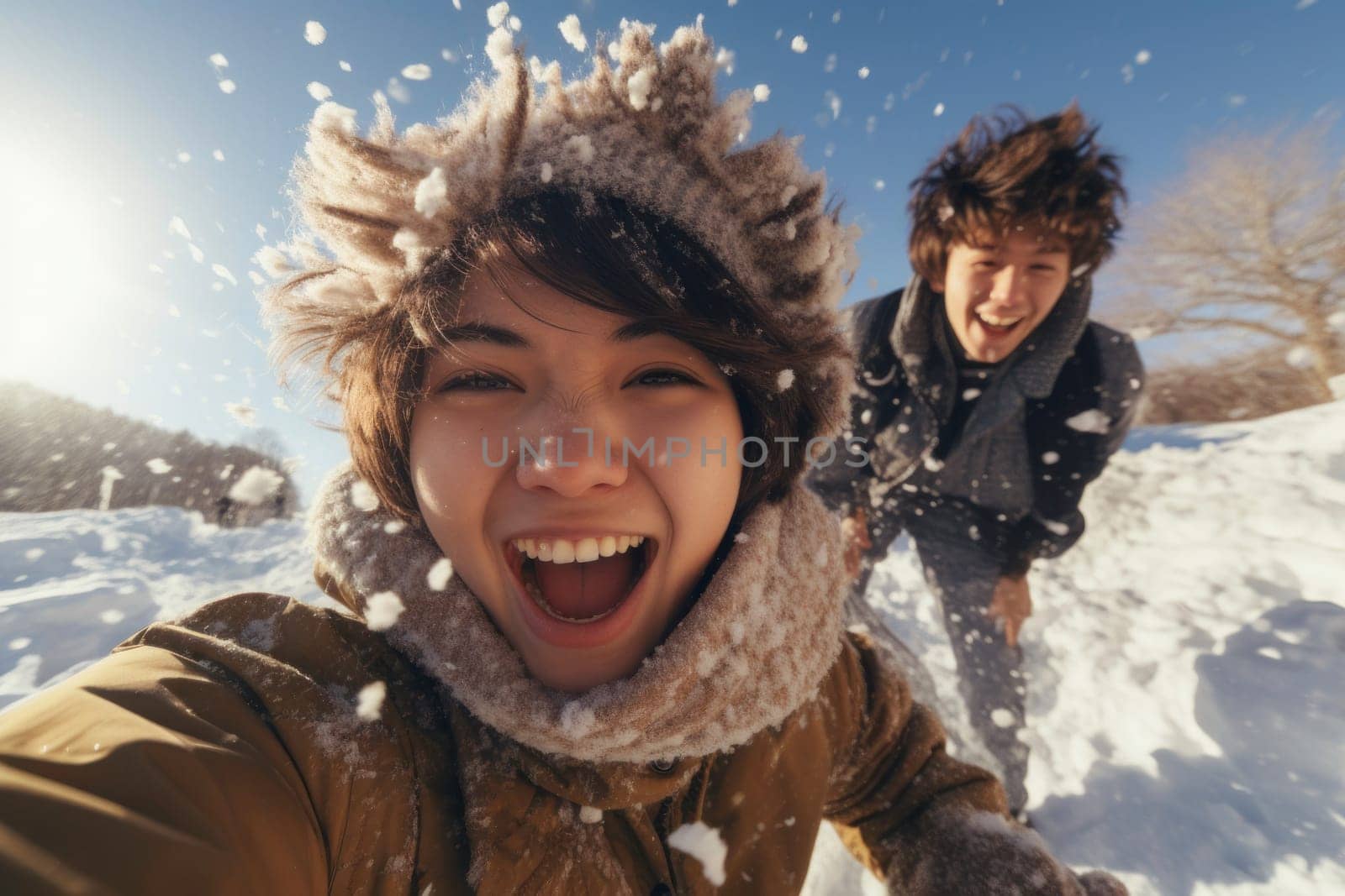 Excited friends enjoying play in the snow, laughing and having fun. Friends enjoying snowball fight. Winter holiday. Girl taking selfie. Positive laughing teenagers enjoying snowy winter day on holidays. Wintertime