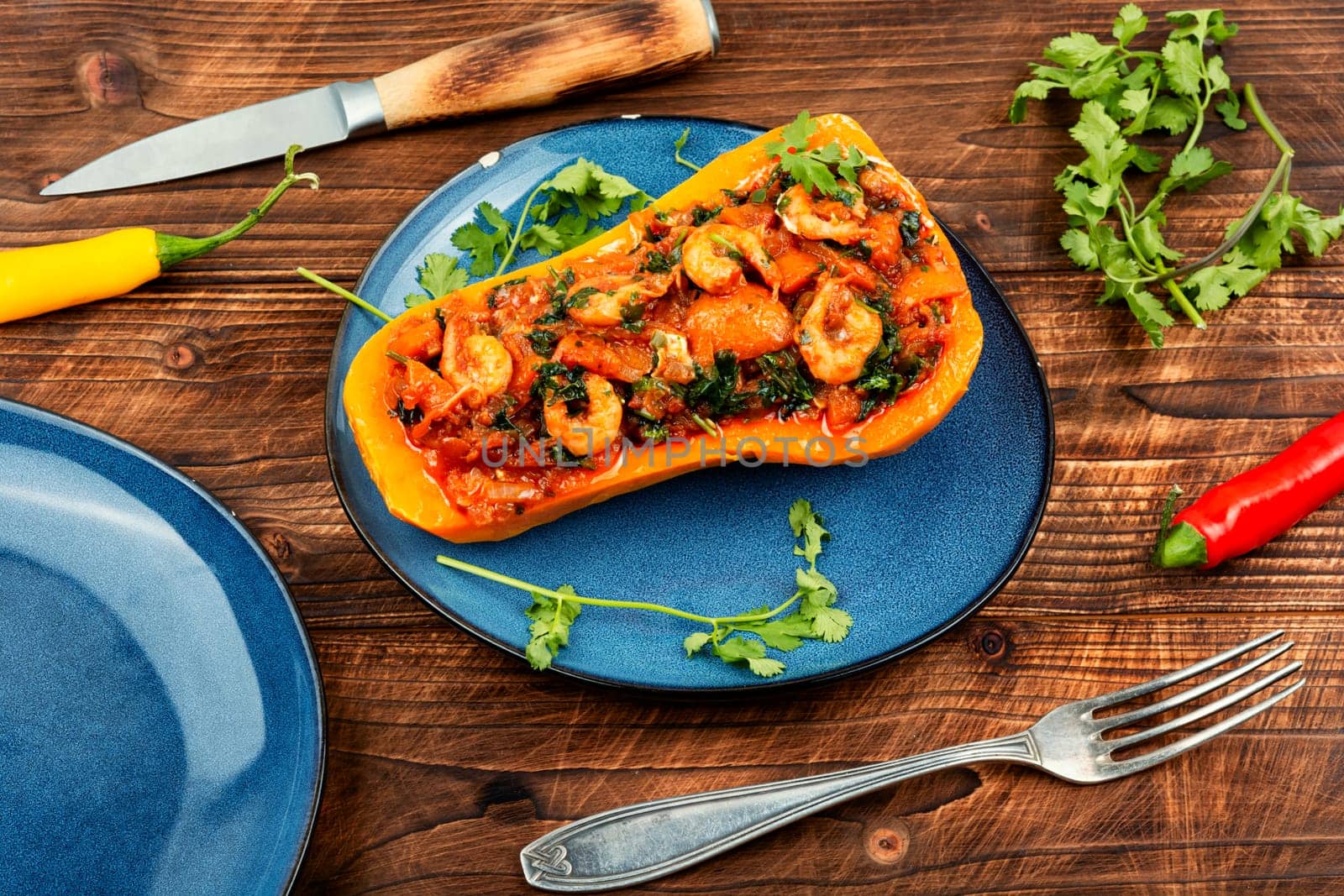 Roasted autumn butternut squash or pumpkin stuffed with peppers, tomatoes and shrimp.