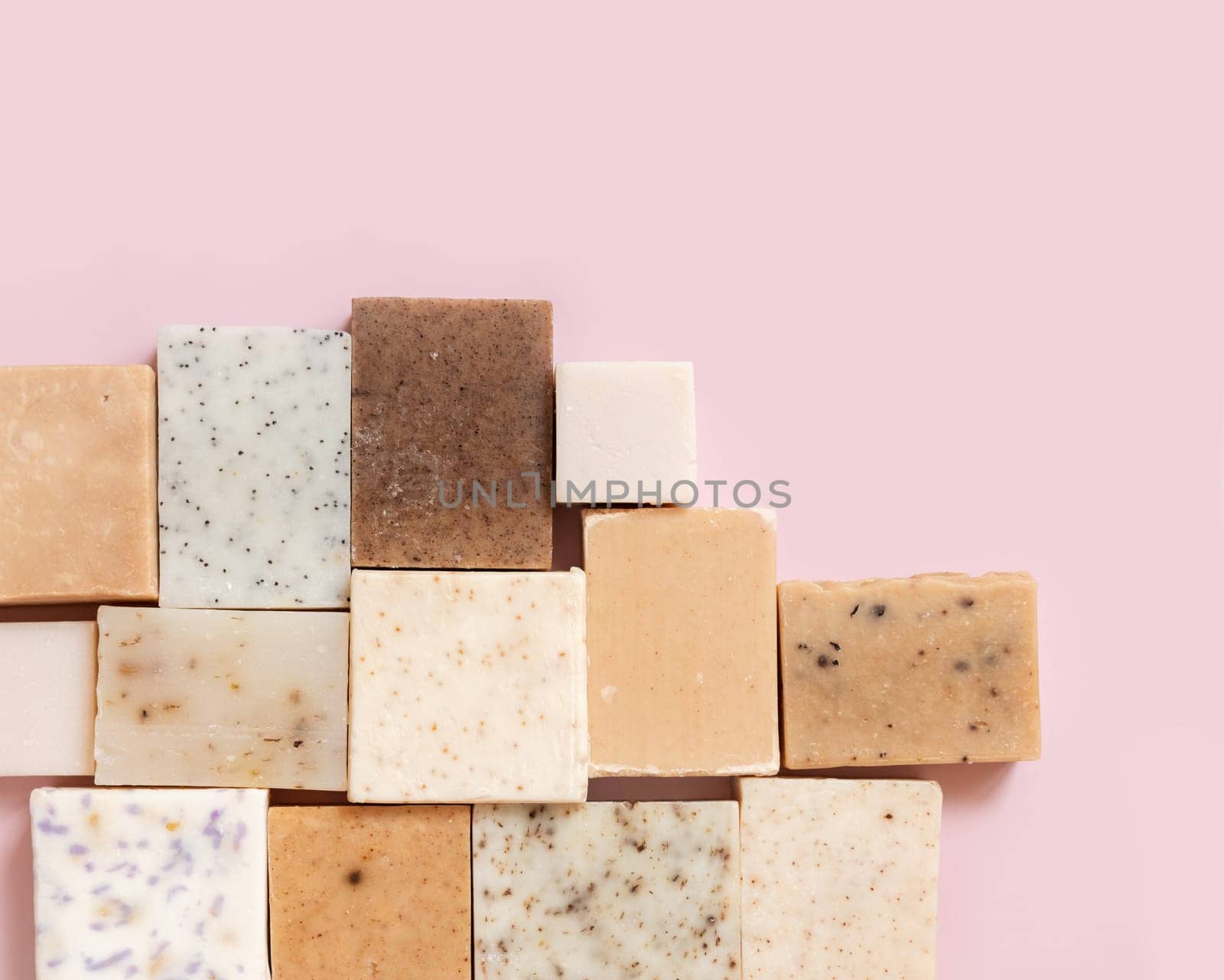 Beige and brown handmade soap bars on light pink top view, copy space. Natural herbal products for Spa and skin care. Using organic handmade skincare products in everyday routine