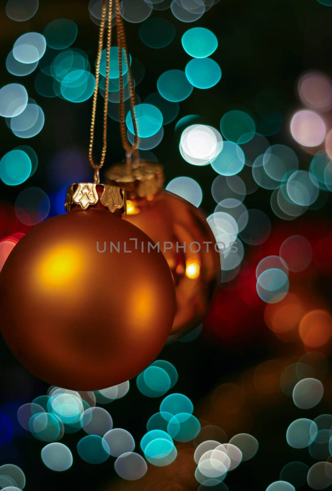 Gold Christmas bauble ball decoration ornament hanging from Christmas tree, bokeh lights background