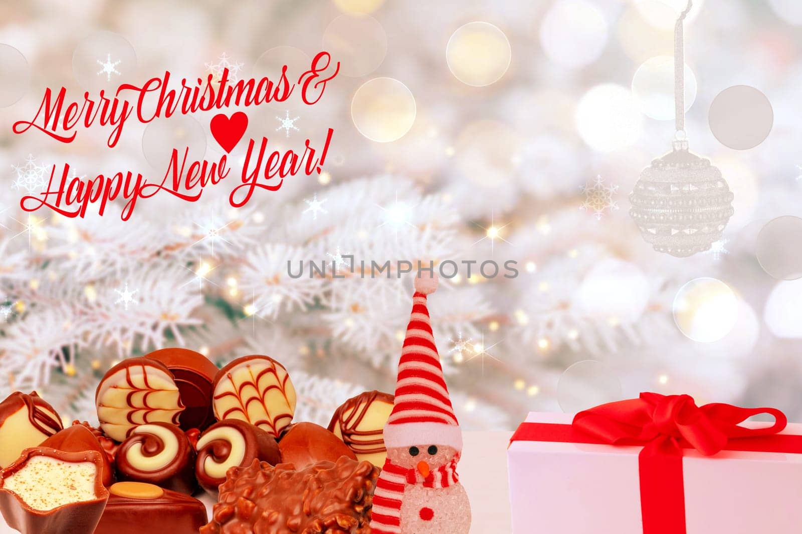 Merry Christmas and Happy New Year greeting card. Various chocolate candies sweets, a cute winter snowman and a gift package on table over abstract winter background.