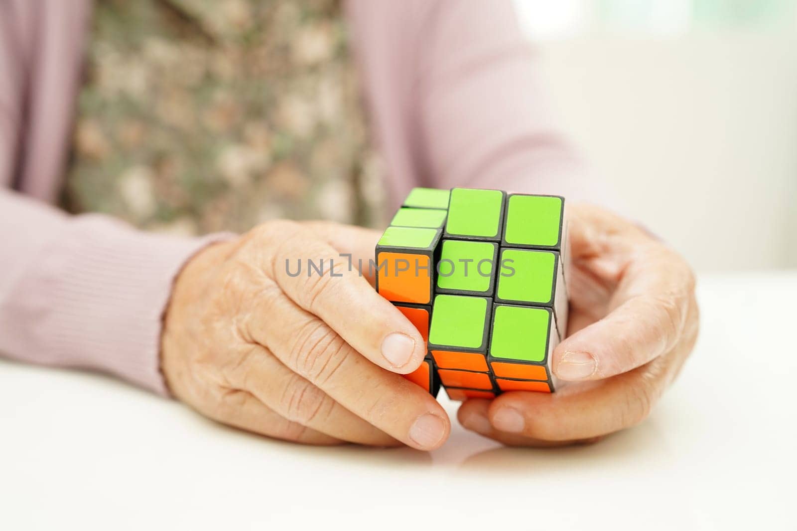 Bangkok, Thailand - May 15, 2022 Asian elderly woman playing Rubik cube game for treatment dementia prevention and Alzheimer disease.