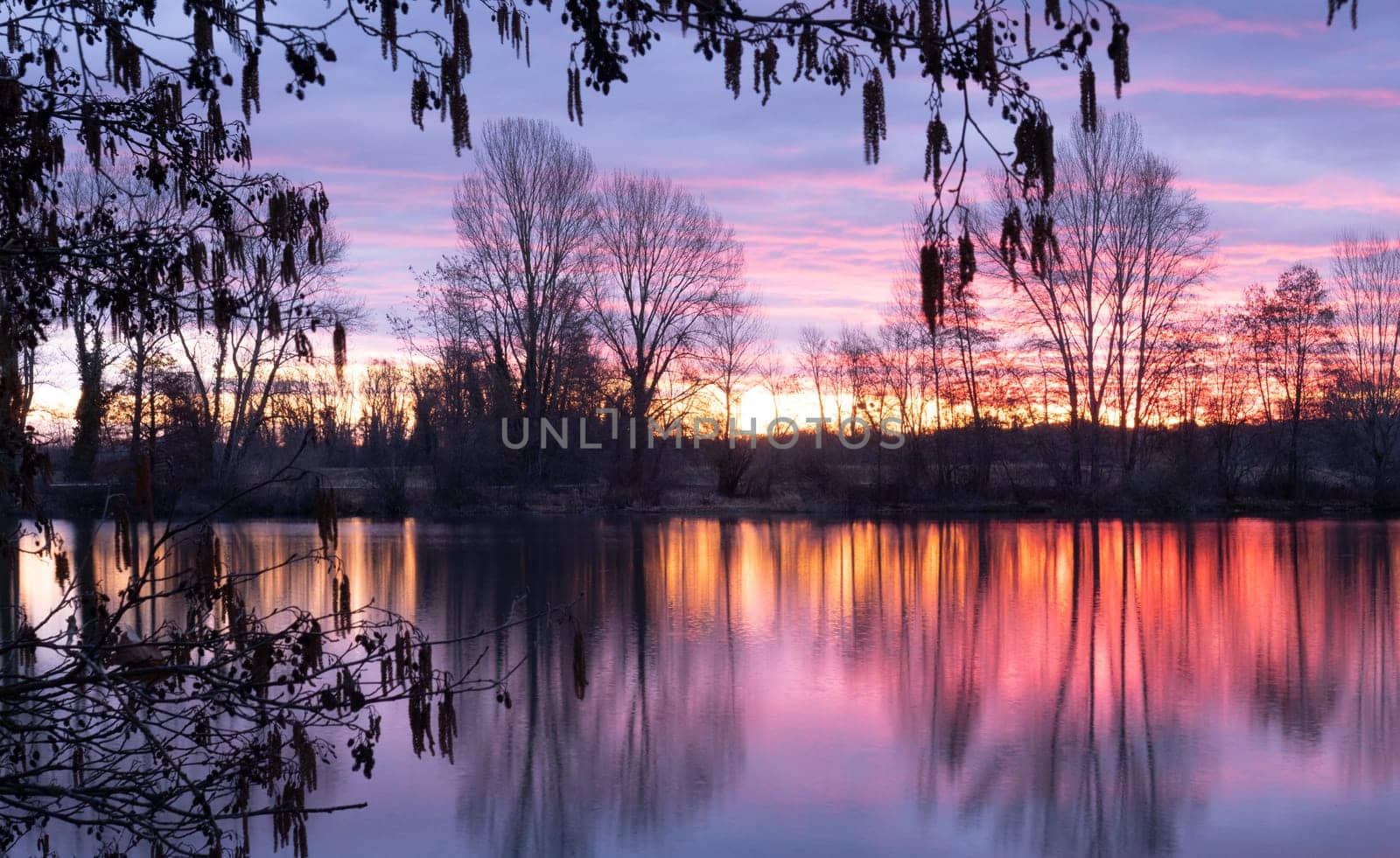 Nightscape photo of Adour French river after blazing red sunset with dramatic clouds floating. Photography taken in France
