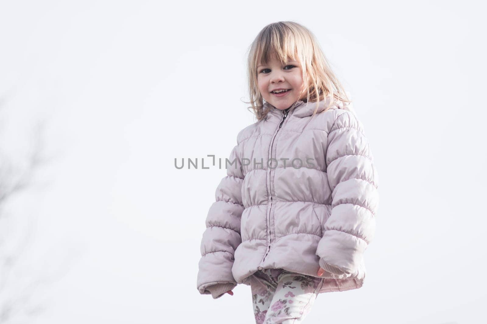 Child portrait of cute trendy little girl in jacket on white background outdoors.