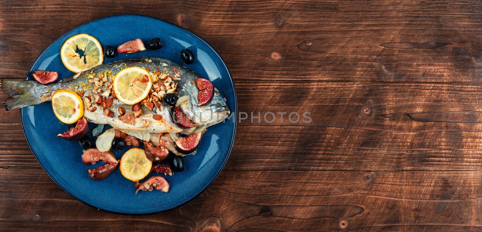 Baked dorado fish with almonds and figs. Autumn recipe. Space for text