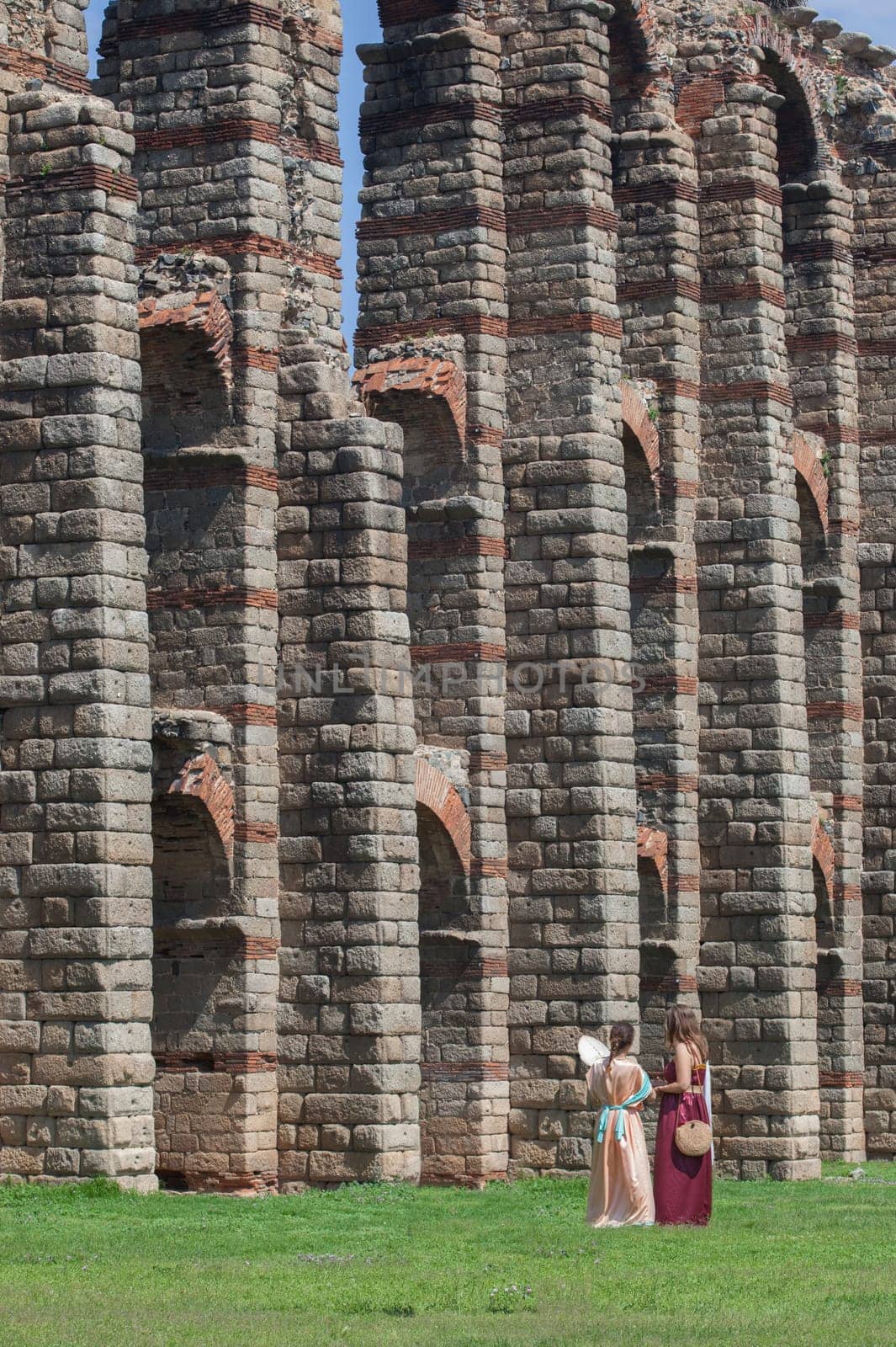Merida, Spain - June 4th, 2023: Young reenactors women beside Los Milagros aqueduct. Emerita Ludica Festival 2023, Merida, Spain