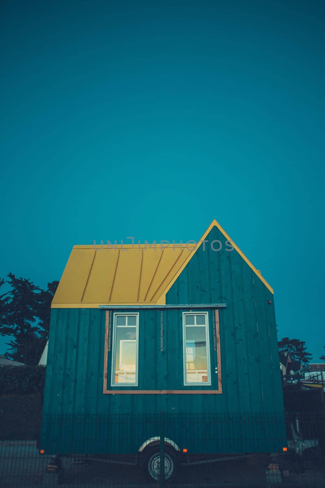 Modern blue tiny house on wheels at the twilight. Copy space for text. Vertical photography taken in France