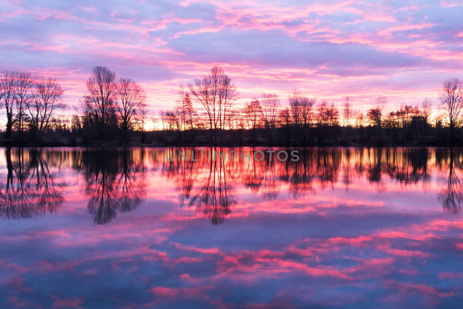 Nightscape at Adour French river in blazing red sunset with dramatic clouds floating. Photography taken in France