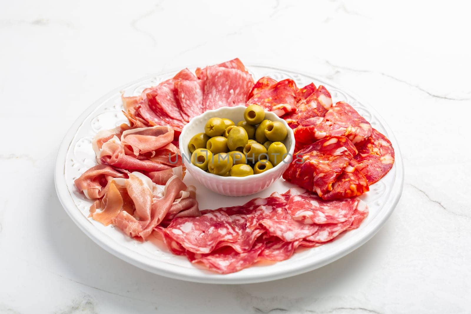 Assortment of Italian and Spanish sliced meat appetizer, prosciutto, salami and ham, with olives