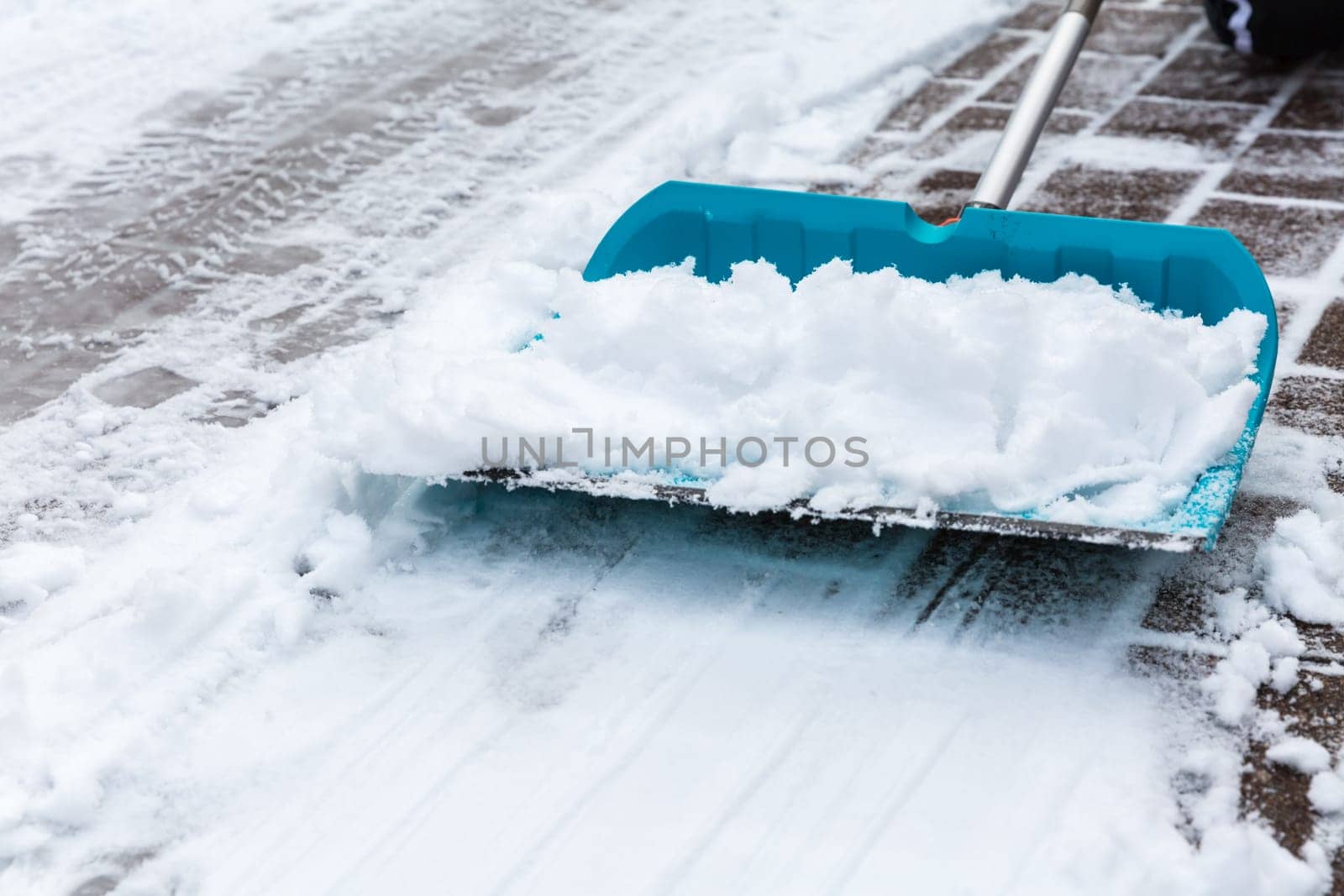 Cleaning snow from sidewalk and using snow shovel