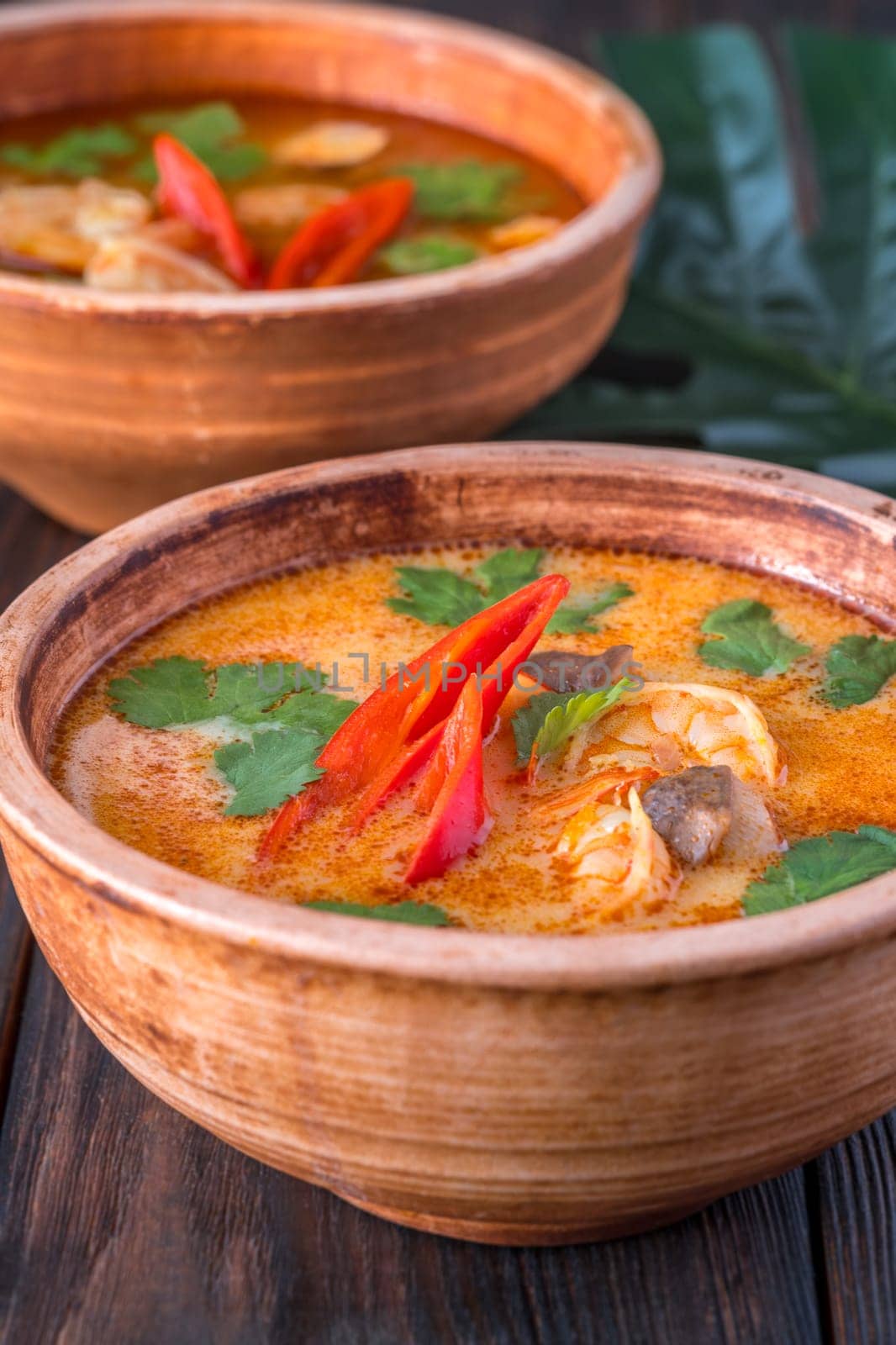 Bowls of tom yum soup on wooden background
