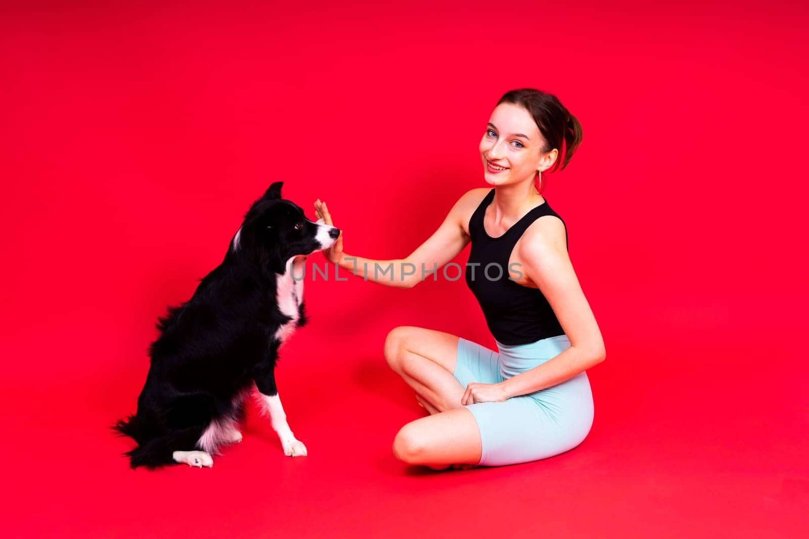 Woman with cute dog border collie is in a studio. Sport with pet